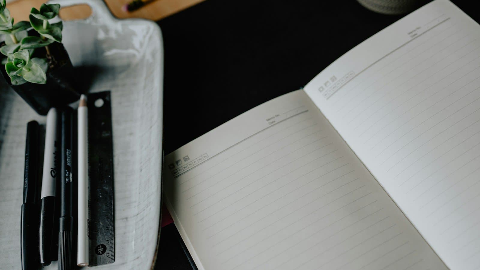 An open notebook and writing tools on a desk, photographed by Kelly Sikkema.
